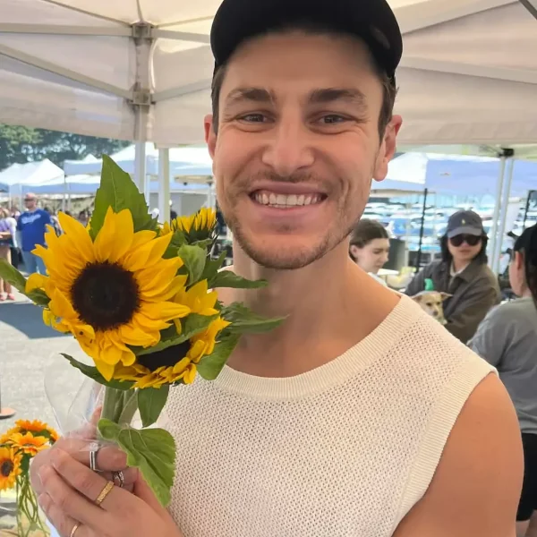 Corey Micari - Founder of the Micari Method holding a yellow sun flower.